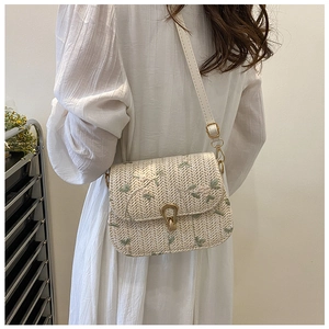 Detail of summer straw crossbody bag with green floral embroidery and leather strap
