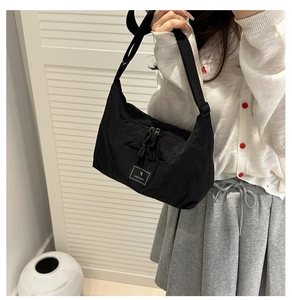 Detail of black nylon hobo bag with adjustable strap and brand logo on a female model