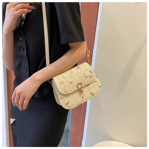 Detail of white straw crossbody bag with green floral embroidery and gold metal clasp
