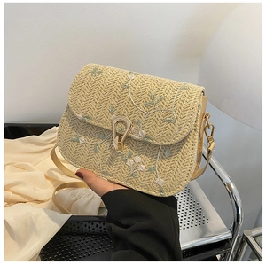Detailed close-up of straw crossbody bag with floral embroidery and gold clasp