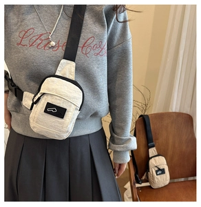 Détail du sac de poitrine beige avec bandoulière noire et écusson logo pour femmes