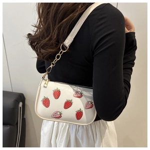 Detail of white strawberry print shoulder bag with gold chain strap and zipper