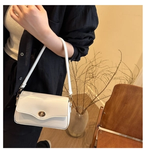 Vue détaillée d'un sac à bandoulière en cuir blanc avec fermoir rotatif doré sur un mannequin
