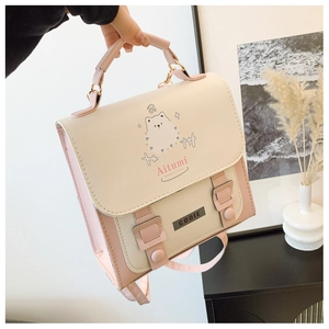 Detail of light pink PU leather handbag featuring cartoon dog illustration and buckles