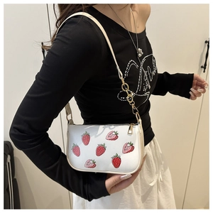 Detail showing white PU leather bag with strawberry prints and golden chain strap