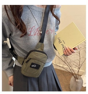 Detail of army green nylon chest bag with adjustable strap and front zipper compartment