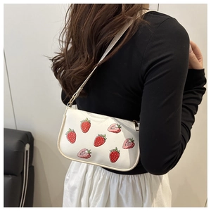 Seitenansicht der weißen Schultertasche mit Erdbeerdruck an der Schulter des Models
