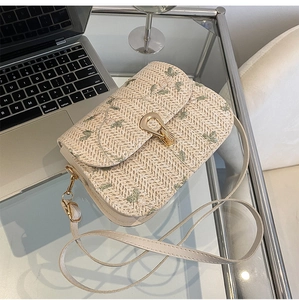 Detailed macro view of woven straw bag with floral embroidery and gold metal clasp