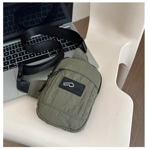 Vue détaillée du sac de poitrine vert olive avec sangle noire et texture de tissu
