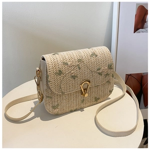Detail of floral embroidery and gold metal clasp on straw shoulder bag for women