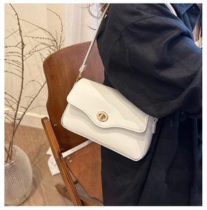 Vue détaillée d'un sac baguette blanc avec fermoir rotatif doré et bandoulière en cuir