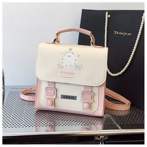 Detailed close-up of pink and cream mini backpack with cartoon print and metal logo