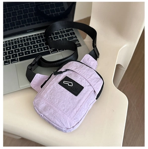 Détail d'un sac de poitrine en nylon violet clair avec sangle réglable et tissu texturé