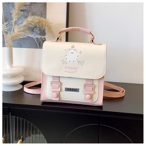Close-up of pink and cream mini backpack with cartoon print and decorative buckles