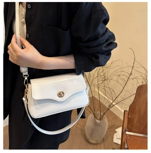 Détail latéral d'un sac à bandoulière crème avec fermoir rotatif doré élégant
