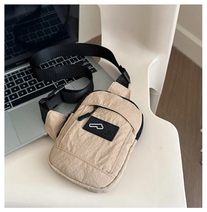 Détail d'un sac bandoulière en nylon kaki avec fermeture éclair noire et logo