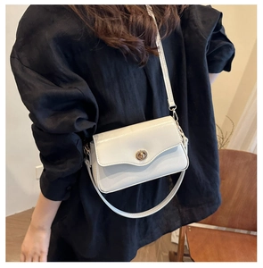 Détail d'un sac à bandoulière élégant avec fermoir doré rotatif et texture en cuir lisse