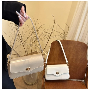 Détail de sacs baguette vernis beige et blanc avec fermoir rotatif en métal doré élégant