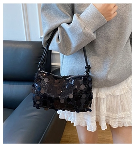 Close-up of black sequined shoulder bag featuring large round sequins and metal zipper detail