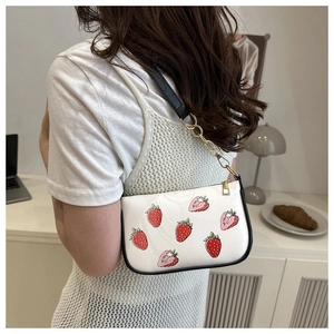 Detail of white PU shoulder bag featuring red strawberry print and golden metal chain strap