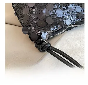 Detail view of shimmering black sequins and woven knotted zipper pull on fashion handbag