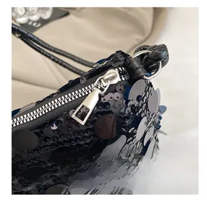Close-up of smooth silver metal zipper on black sequined luxury crossbody pillow bag
