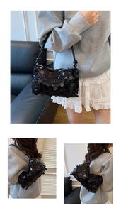 Detailed close-up of a black sequined underarm bag with shimmering texture and knotted strap