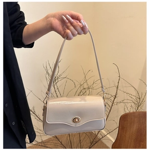Détail macro du sac baguette beige brillant avec son fermoir tournant doré élégant