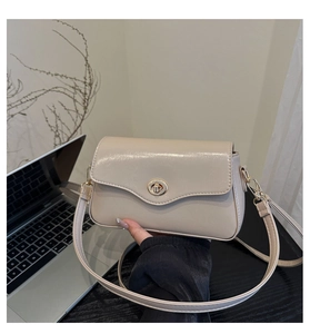 Détail d'un sac bandoulière beige à finition brillante avec fermoir rotatif doré
