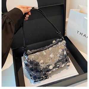 Top view of silver sequin shoulder bag in a luxury gift box with fashion magazines