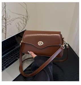 Vue détaillée du sac à main en cuir marron brillant avec fermoir rotatif doré et bandoulière