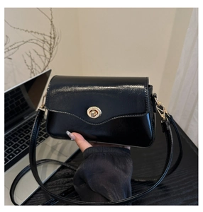 Détail du sac à bandoulière en similicuir noir brillant avec boucle rotative dorée