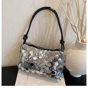Detail of silver sequin shoulder bag with black leather strap and knot accent decoration