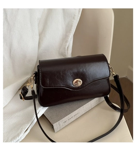 Détail du sac bandoulière café vintage avec fermoir rotatif doré et texture cuir huilé