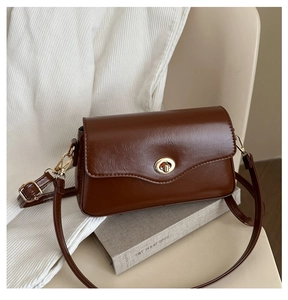 Détail du sac à main vintage marron avec rabat ondulé et fermoir doré ovale élégant