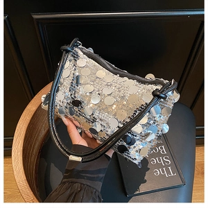 Close-up of shiny silver sequin handbag with black woven handle and zipper closure