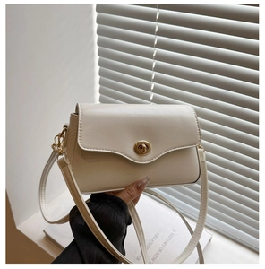 Détail du sac à bandoulière en cuir blanc cassé avec fermoir rotatif doré de luxe
