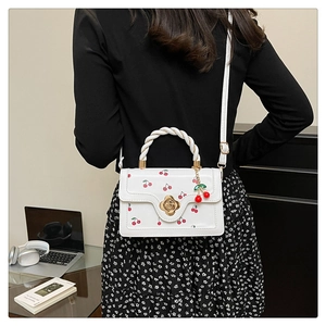 Petit sac bandoulière blanc à motifs cerises et fermoir camélia porté par un mannequin