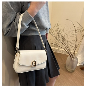 Détails de ce petit sac carré blanc cassé avec une boucle dorée et texture haut de gamme