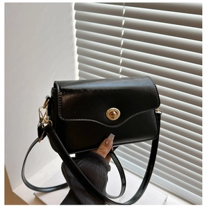Détail d'un sac baguette noir minimaliste avec un fermoir rotatif doré brillant