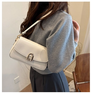 Gros plan du sac bandoulière en cuir blanc avec une boucle en métal doré en forme de U