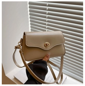 Détail du sac baguette beige clair avec fermoir rotatif doré et bandoulière