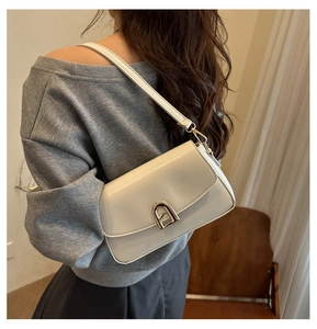 Détail latéral d'un sac bandoulière blanc cassé avec fermoir arche doré et bandoulière fine