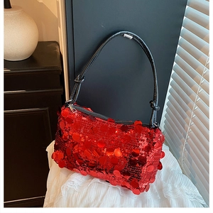 Close-up of vibrant red sequined handbag with black leather strap and silver zipper