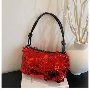 Detail of red sequined handbag with black twisted handle and metallic zipper closure