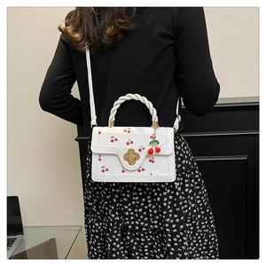 Detailed view of cherry print bag with twist handle and golden flower metal lock