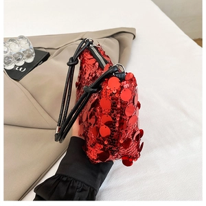 Close-up of red sequined handbag with black shoulder strap and silver metal zipper