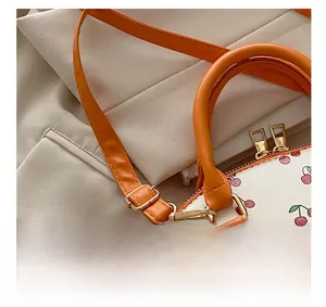 Detail of golden zipper and orange leather strap on the cherry print bucket bag