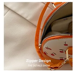 Detail of orange cherry print shell bag showing the metal zipper and interior space