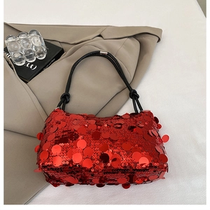 Detail of red sequined shoulder bag with black knotted straps on stylish beige blazer